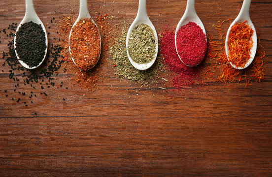 Spices in spoons on a wooden background