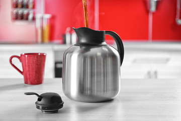 Pouring coffee into thermos kettle on kitchen counter