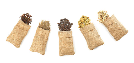 Spices in sacking bags on white background, top view