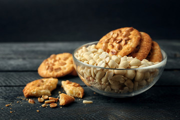 Peanut cookies and bowl with nuts on wooden table