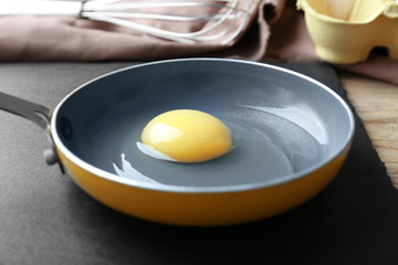 Fresh raw egg in frying pan on slate plate