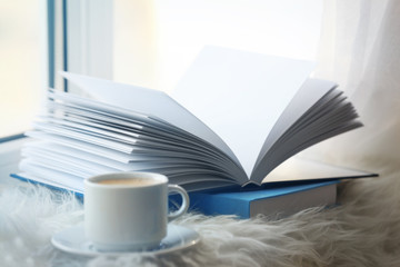 Cup of coffee and books on windowsill