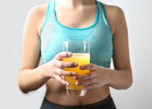 Closeup of sporty woman holding glass of orange juice