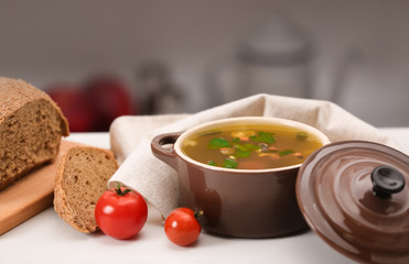 Pot with fresh vegetable soup and bread on kitchen table