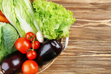 Fresh vegetables in basket on wooden table