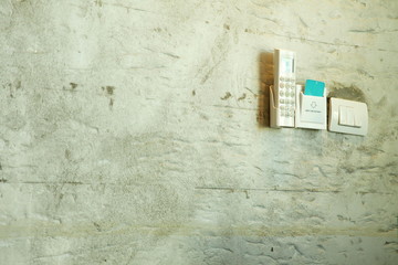 The remote control of air conditioner and room keycard holder put on the concrete wall.