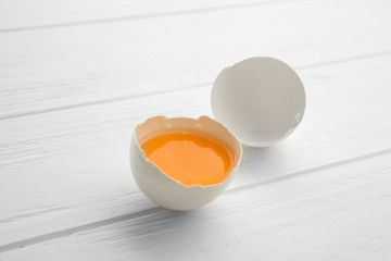 Raw egg with yolk on wooden background