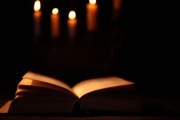 Bible and burning candles on background