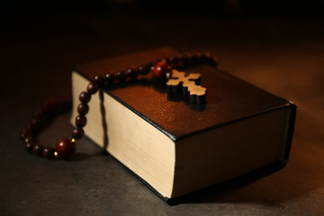 Bible with rosary on dark background