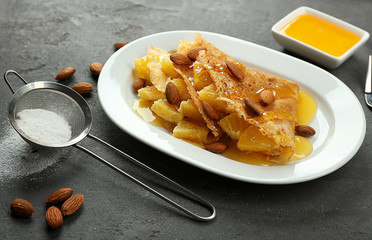 Tasty pancakes with pineapple and almonds on plate