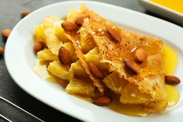 Tasty pancakes with pineapple and almonds on plate