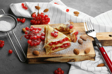 Delicious pancakes with viburnum on wooden board