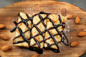 Delicious pancakes with chocolate on wooden board