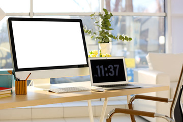 Workplace with computer and laptop on table in modern room