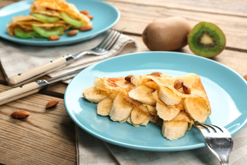 Blue plate with delicious pancakes on wooden table