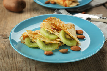 Blue plate with delicious pancakes on wooden table