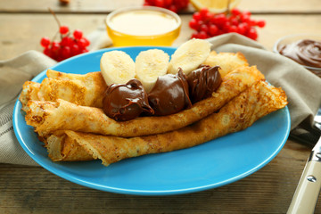 Delicious pancakes with chocolate and banana on blue plate