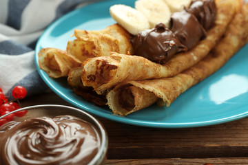 Delicious pancakes with chocolate and banana on blue plate, closeup