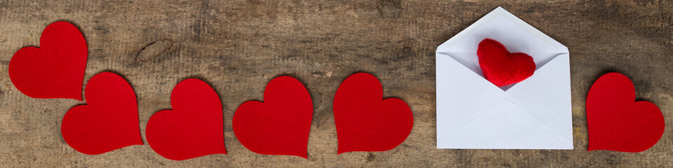 Love letter envelope with red hearts on wooden background