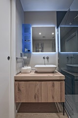 interior view of a modern bathroom in foreground the countertop washbasin and wood furniture the floor isa made of wood