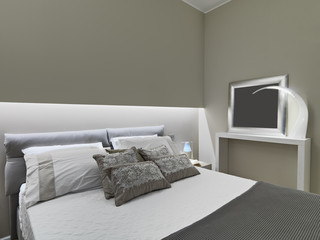 interior view of a modern bedroom in foreground several pillowa on the bed and wall lamp