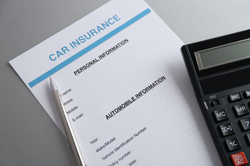 Car insurance form, calculator and pen on table