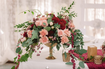 Wedding table decoration with the red and pink flowers on the white cloth