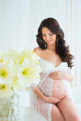 Beautiful pregnant in light white lace negligee in the bathroom