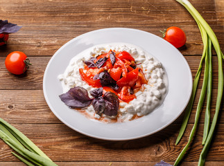 Salad with cottage cheese and tomatoes on wood table.