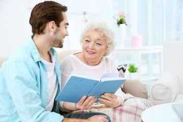 Young man with grandmother reading book on couch at home