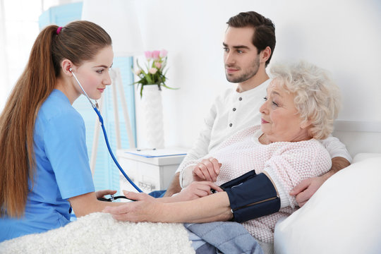 Nurse measuring woman's blood pressure with tonometer indoors