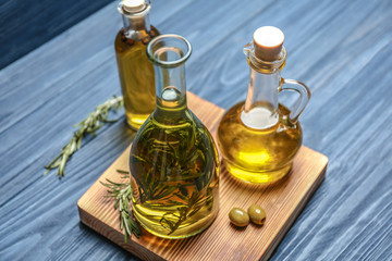 Bottle with olive oil and herbs on wooden background