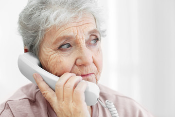 Elderly woman talking by telephone at home