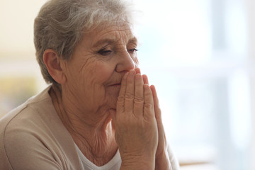 Praying elderly woman at home