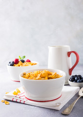 Corn flakes with berries and milk on light gray background. Copy space. Healthy breakfast concept.