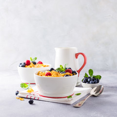 Corn flakes with berries and milk on light gray background. Copy space. Healthy breakfast concept.