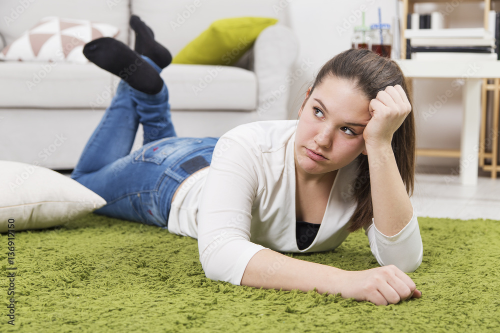 Wall mural young upset teenage girl lying on the floor. teenage problems