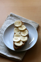 Slice of rye bread with peanut butter and banana. Top view. 