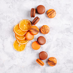 Different types of macaroons: chocolate and orange on a gray background