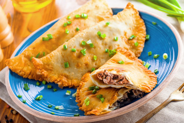 Chebureki on a plate. National Ukrainian, Russian, Turkish, Romanian and Tatar food. Meat pastry meal on a table. Top view close-up shot.