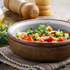Traditional Israeli healthy meal Ptitim with tomatoes, cucumber and onion for delicious healthy breakfast. Classic Moroccan couscous with vegetables.
