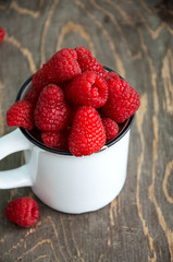 Fresh raspberries in a big white cup on a wooden table