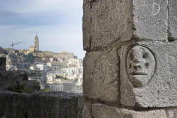 face sculpted on a wall in matera old town, italy