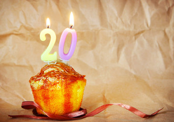 Birthday cake with burning candles as number twenty on brown paper background
