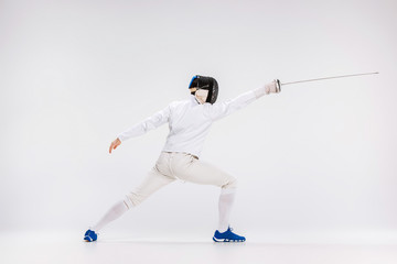 Obraz premium Man wearing fencing suit practicing with sword against gray