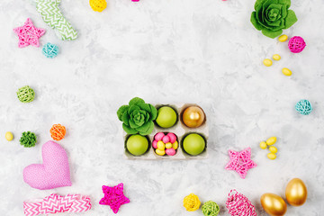 Easter eggs, candy and succulent in paper tray on spring decoration background. Flat lay, top view