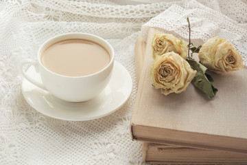 Obraz na płótnie Canvas Cup of coffee with milk on windowsill and book with dry rose as decor on lace. Vintage.