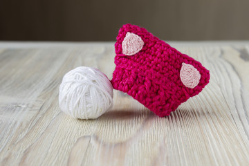 Fototapeta na wymiar Knitted crochet small pink pussy hat. Women's pussy hat for feminists march protest. Creative craft work