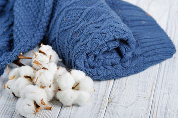 Fototapeta na wymiar Still life with blue trendy winter knitted sweater and delicate white flowers of cottons
