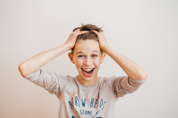 Portrait of a surprised  teenage boy holding his head on a light background - 136920771